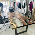 Hackberry wood and clear epoxy table with straight edges and a dark metal base at Sirus’s clothing shop in Dubai.