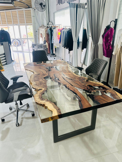 Hackberry wood and clear epoxy table with straight edges and a dark metal base at Sirus’s clothing shop in Dubai.