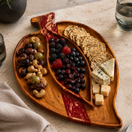 Leaf-shaped walnut wood serving board with a red epoxy river running along the carved midrib, handmade in Dubai.