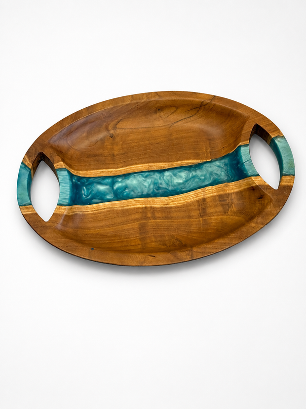 Oval walnut serving tray with a river-blue pearl epoxy band running across the centre and two carved oval handles, handmade in Dubai.